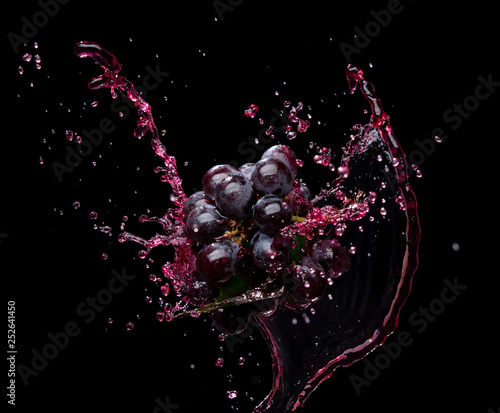 Foto Bunch of grapes with red juice splash isolated on black background