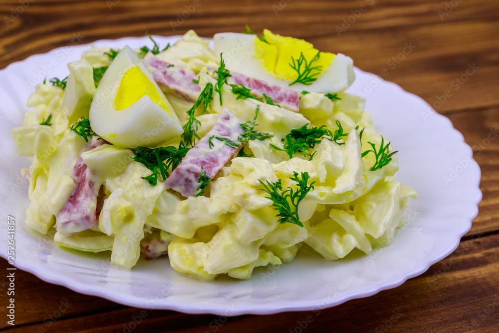 Salad with chinese cabbage, onion, sausage, eggs and mayonnaise on wooden table Salad with chinese cabbage, onion, sausage, eggs and mayonnaise on wooden table