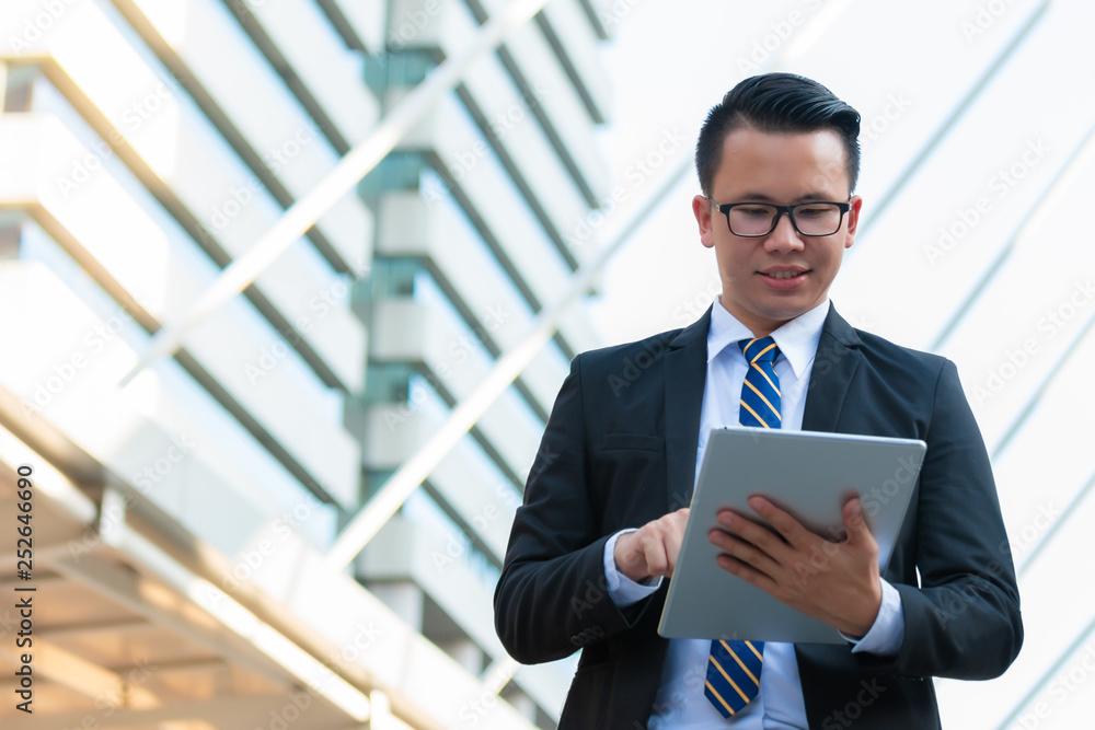 Happy businessman dressed in black suit using digital tablet outside office and smile. Digital technology concept. Happy businessman dressed in black suit using digital tablet outside office and smile. Digital technology concept.