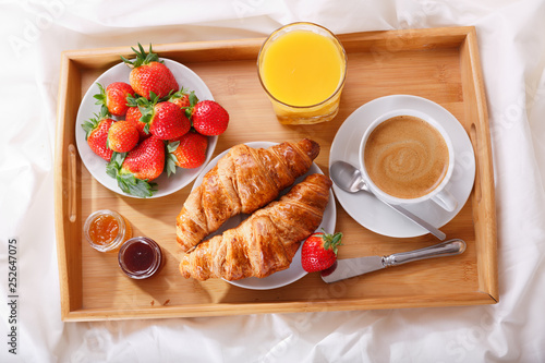 breakfast tray in bed : coffee, croissants, orange juice and fresh strawberries