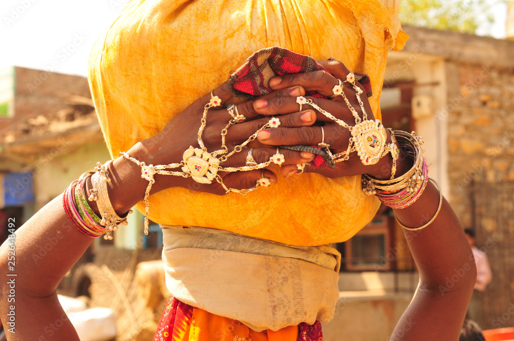 Gujarat: A young woman carring water on her head and showing her bracelets