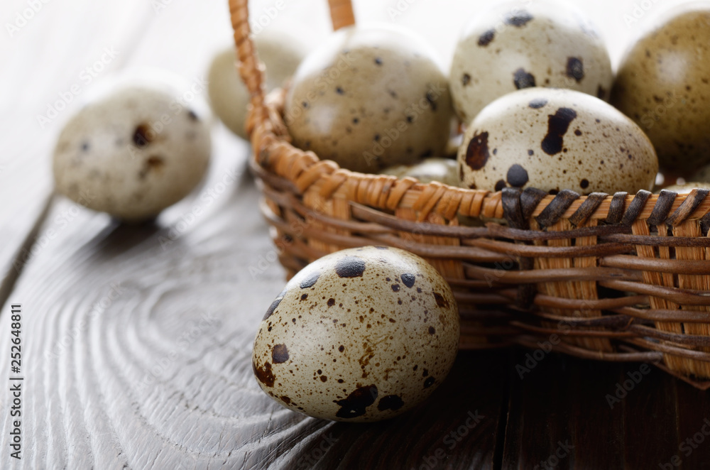 Fresh organic quail eggs in small wicker basket on rustic kitchen table. Space for text Fresh organic quail eggs in small wicker basket on rustic kitchen table. Space for text