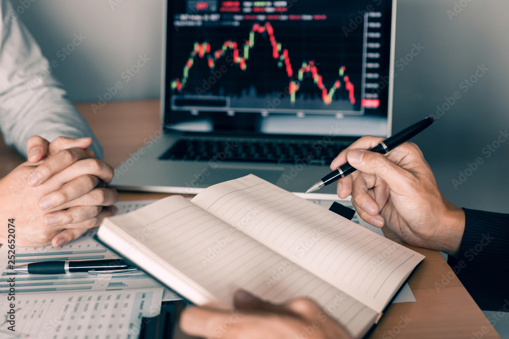 Investors are using a pen to writing data for the company that is analyzing the shares with colleagues at the office. Investors are using a pen to writing data for the company that is analyzing the shares with colleagues at the office.