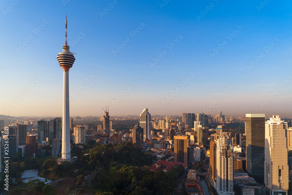 Fototapeta premium Menara Kuala Lumpur Tower with sunset sky. Aerial view of Kuala Lumpur Downtown, Malaysia. Financial district and business centers in urban city in Asia. Skyscraper and high-rise buildings at noon.