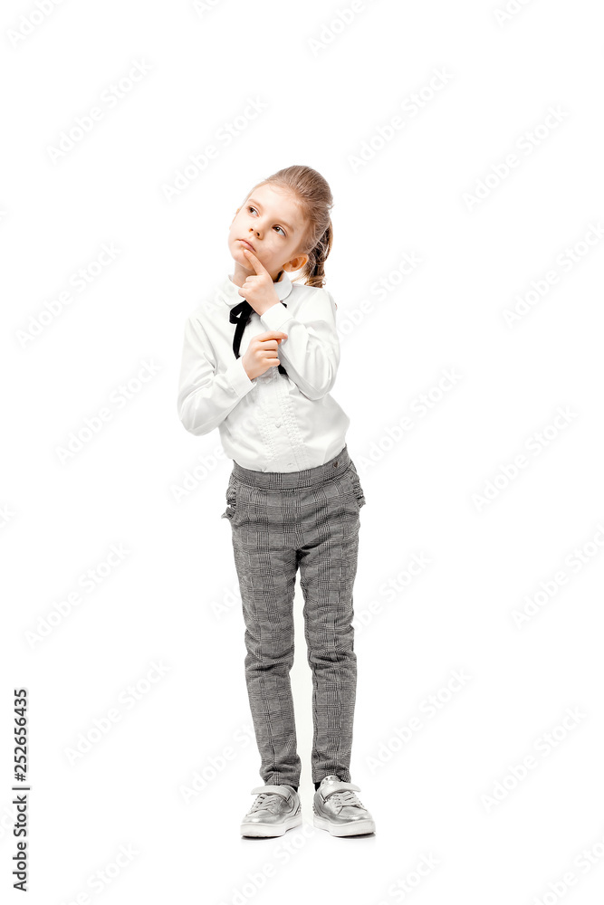 Beautiful little girl dressed like a School girl - in white shirt and gray pants, rounded glasses standing near white wall and posing thoughtful like model.