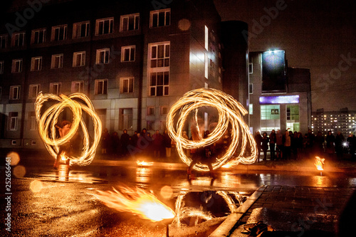 Night performance fire show in front of a crowd of people on the street in night, soft focus background.