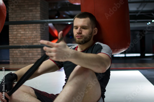 Caucasian man sitting on the ring and preparing to the training