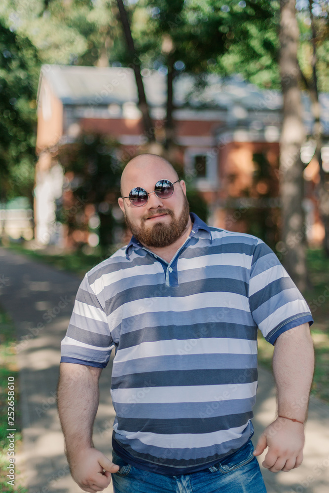 .Young man with round glasses and overweight in the park. .Young man with round glasses and overweight in the park.