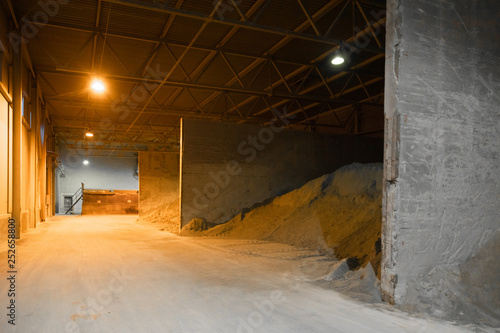 Mountains of sand in a cement factory in a Dark room with light from the lanterns