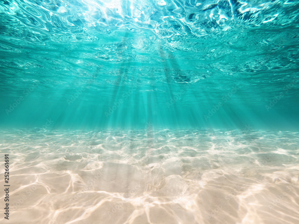 underwater background  deep blue sea and beautiful light rays with sandy floor