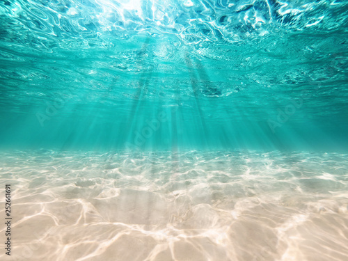 underwater background  deep blue sea and beautiful light rays with sandy floor photo