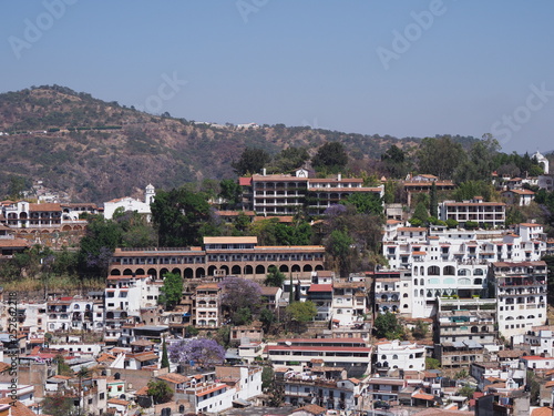 Housing estate on slope at cityscape landscape of historical Taxco city with jacaranda trees in Mexico photo