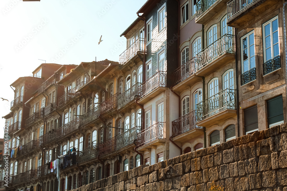 Beautiful old buildings in the old town / old city of Porto near river Douro with balconies, seagull and sunrays (Porto, Portugal, Europe)