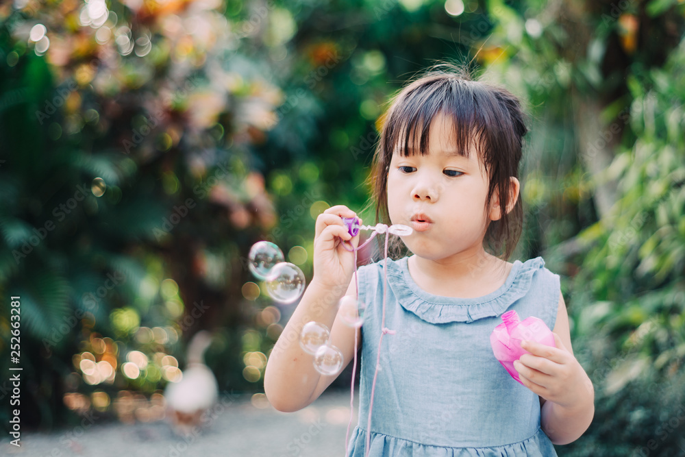 Outdoors activity : Cute kid blowing bubbles soap in the garden. Picture for concept of childhood in school age. Outdoors activity : Cute kid blowing bubbles soap in the garden. Picture for concept of childhood in school age.