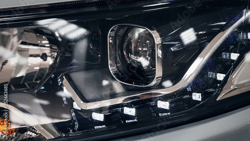 Closeup headlights of a modern car. Detail on the front light of a car. Modern and expensive car concept. The car is in the showroom © svetlichniy_igor