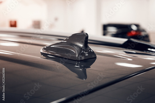 Close-up GPS antenna shark fin shape on a roof of car for radio navigation system. Antenna shark fin on blurry background. Car detail photo