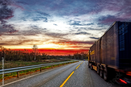 Truck transport on the road at sunset.