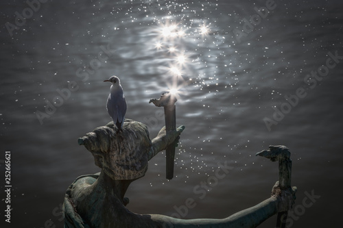 Mouette sur une sculpture à Prague. Reflets dans l'eau de la Vlatva photo