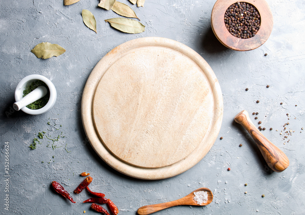 Fotografie Cutting board and spices on a gray background.