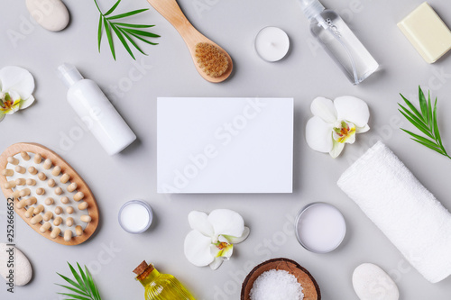 Spa, aromatherapy, beauty treatment and wellness background with massage brush, towel, orchid flowers and cosmetic products. Top view and flat lay. Empty card for text.