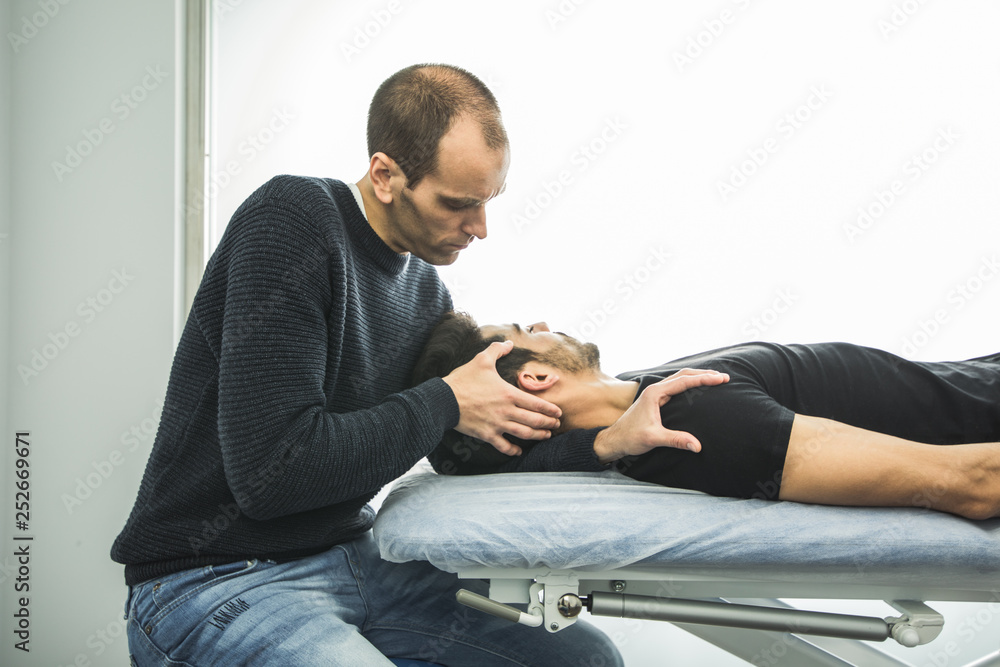 Physiotherapist massaging a young man neck. Concept of physiotherapy and rehabilitation Physiotherapist massaging a young man neck. Concept of physiotherapy and rehabilitation