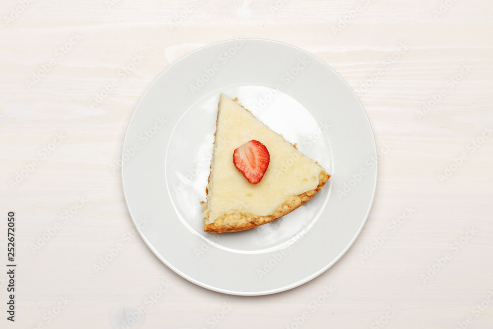 Composition with a piece of cheesecake on a wooden white table. Top view Composition with a piece of cheesecake on a wooden white table. Top view