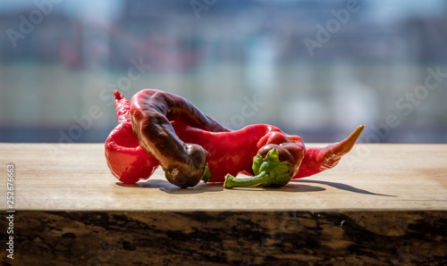 Two cayenne peppers twisted together on a wooden block photo