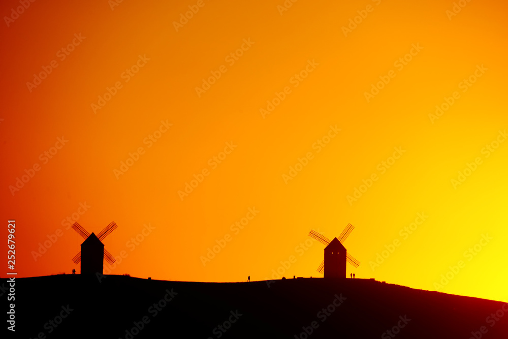 Silhouettes of the Mills of La Mancha and people a sunset.