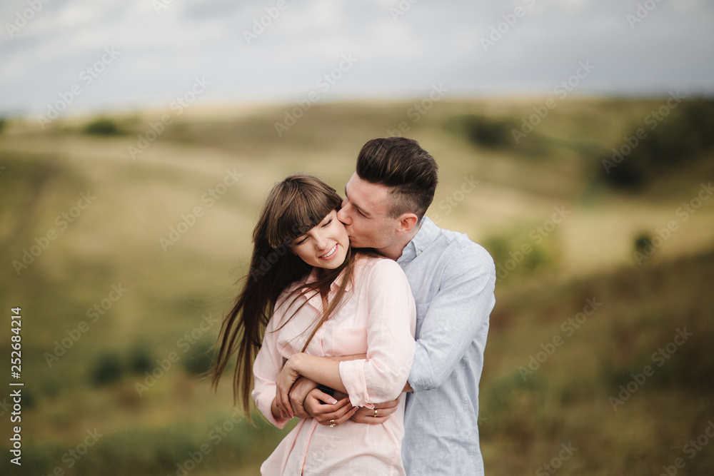 Loving young couple kissing and hugging in outdoors. Love and tenderness, dating, romance, family, anniversary concept.