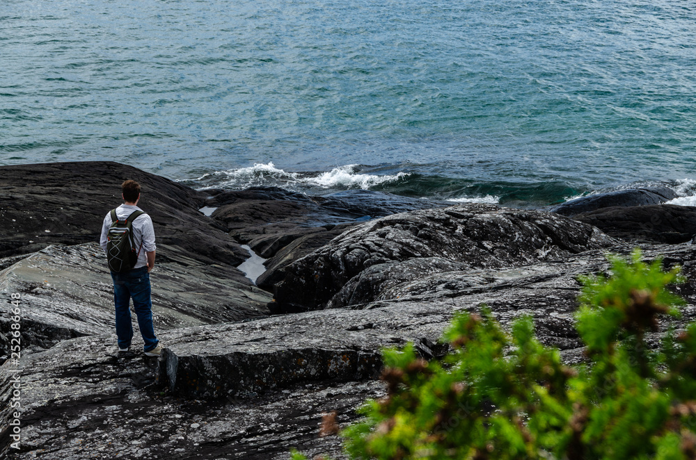 man standing on black rocky shore