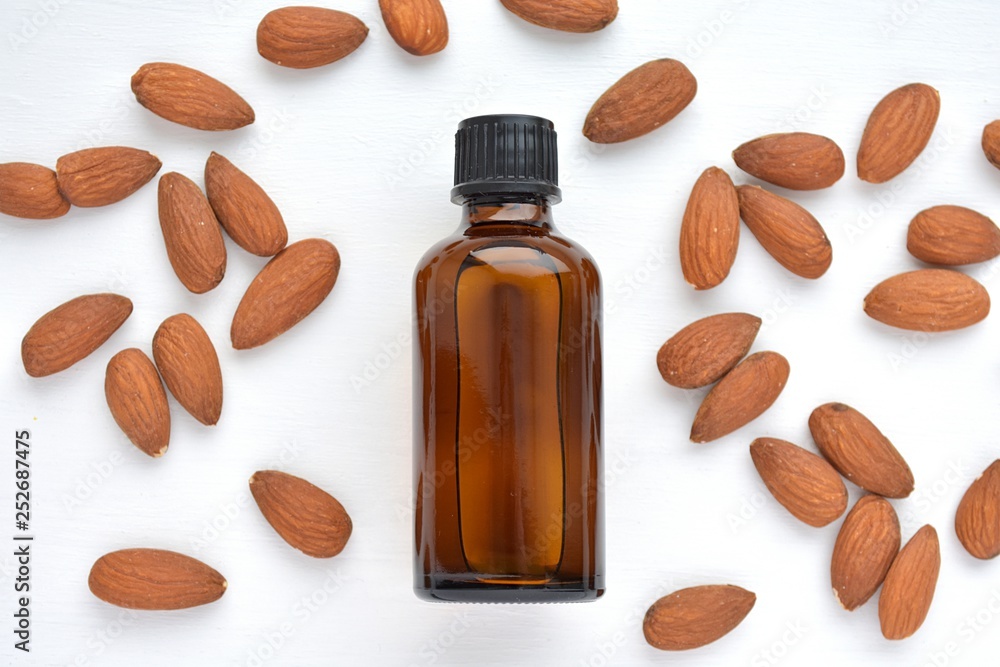 Natural almond oil in brown bottle for cosmetics and nuts, close up, top view. Natural almond oil in brown bottle for cosmetics and nuts, close up, top view.