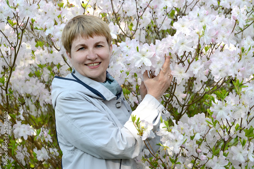 The fifty-year-old woman against the background of the blossoming Shlippenbakh's rhododendron photo