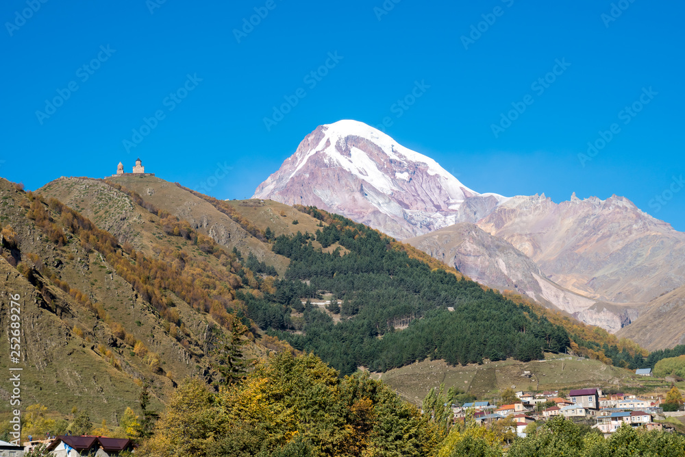 Mount Kazbek (Mkinvartsveri) and Gergeti church at sunny day. Caucasus mountains