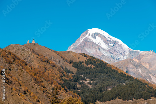 Mount Kazbek (Mkinvartsveri) and Gergeti church at sunny day. Caucasus mountains