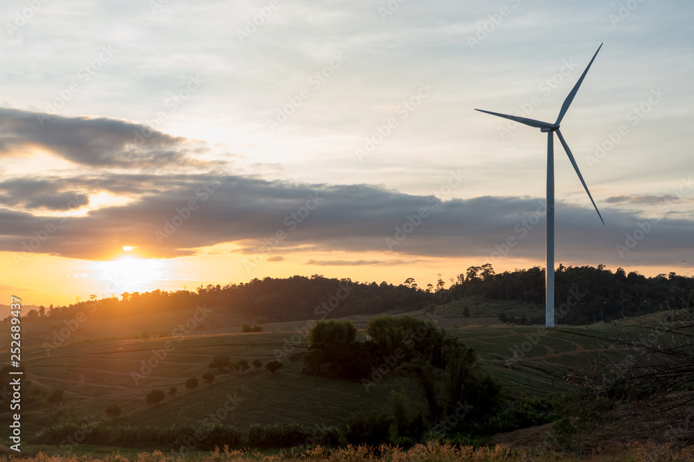 Obraz premium Silhouette of wind turbines on the mountain at sunset.