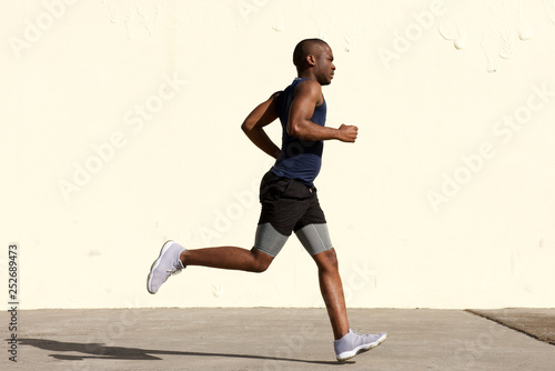 profile portrait of young african american man running by wall