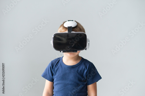 Portrait of happy boy in a virtual reality headset. Attractive kid using vr goggles at home. Entertainment technology and generation Z concept.