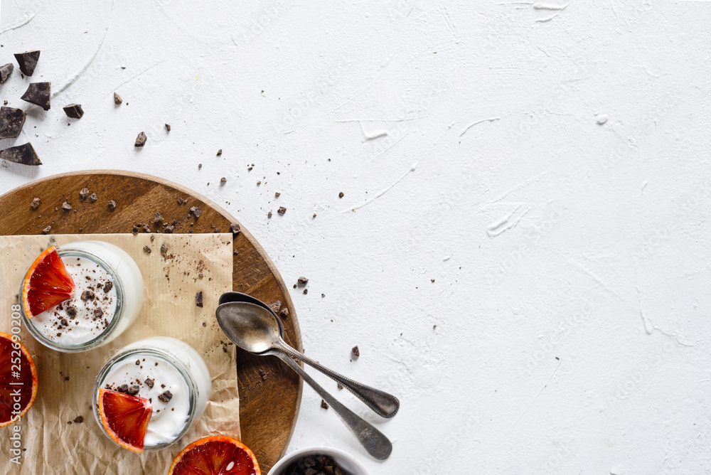 Natural fresh yogurt with blood oranges and chocolate on white background.Yogurt.Eye bird view. Natural fresh yogurt with blood oranges and chocolate on white background.Yogurt.Eye bird view.