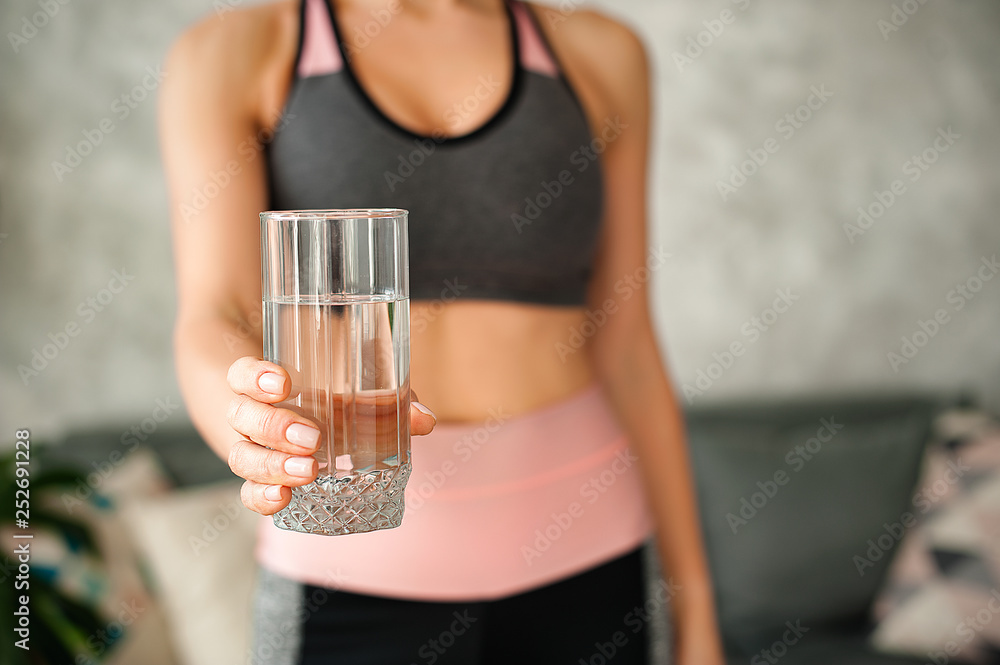 Woman in a tracksuit drinking a glass of water Woman in a tracksuit drinking a glass of water