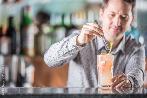 Professional barman making alcololic cocktail drink with grapefruit.