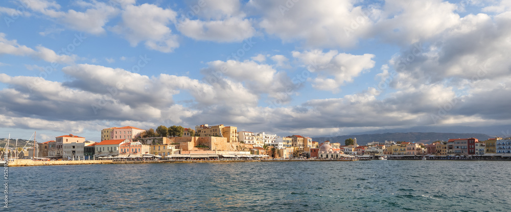 A panorama of the harbor city of Chania. View of the emarald sea, interesting landscapes, colorful houses, a coast view from the cafe. The Mediterranean Sea. A popular tourist resort in the Greece.