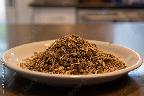 Kava Kava root on plate in a kitchen setting,  A well known organic herbal tea used to relax the body.  Wooden spoon filled with the root.