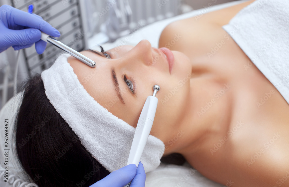 The cosmetologist makes the apparatus a procedure of Microcurrent therapy of a beautiful, young woman in a beauty salon. Cosmetology and professional skin care. The cosmetologist makes the apparatus a procedure of Microcurrent therapy of a beautiful, young woman in a beauty salon. Cosmetology and professional skin care.
