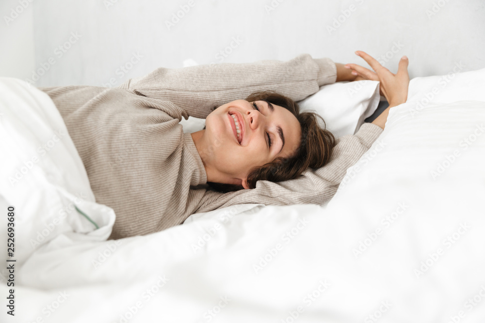 Smiling young girl relaxing in bed in the morning Smiling young girl relaxing in bed in the morning