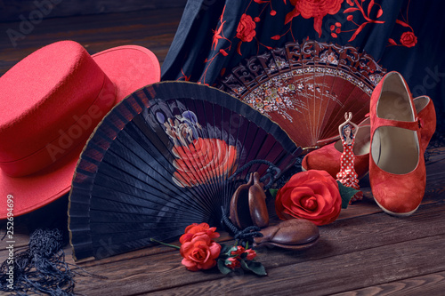 Beautiful and bright accessories for flamenco dance and souvenirs on a wooden background in a low key. Shawl, hat, fan, shoes, castanets