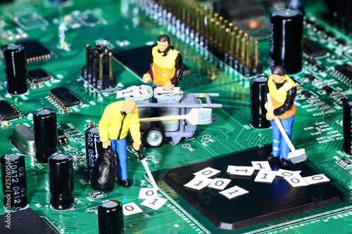 Conceptual diorama image of miniature figure workmen cleaning up binary data from a circuit board