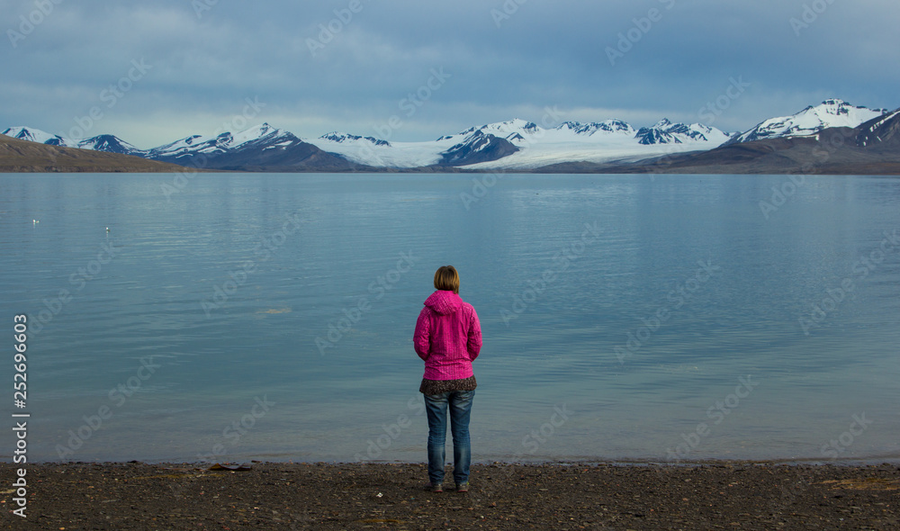 A girl stands on the shores of the Greenland Sea