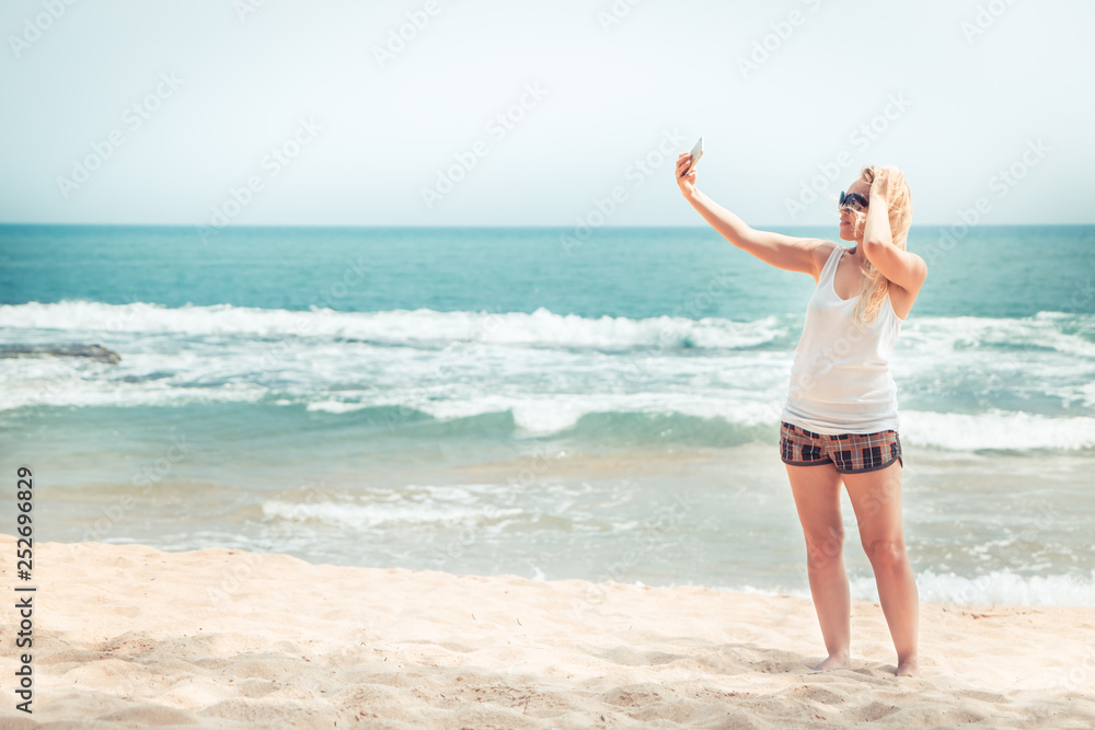 Beautiful lonely woman traveler on beach taking picture selfie on phone during beach travel holidays vacation for social media concept traveling lifestyle vintage style Beautiful lonely woman traveler on beach taking picture selfie on phone during beach travel holidays vacation for social media concept traveling lifestyle vintage style