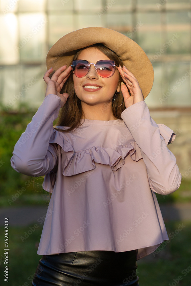 Spring portrait of positive tanned model wears hat and sunglasses, enjoying sunny weather Spring portrait of positive tanned model wears hat and sunglasses, enjoying sunny weather