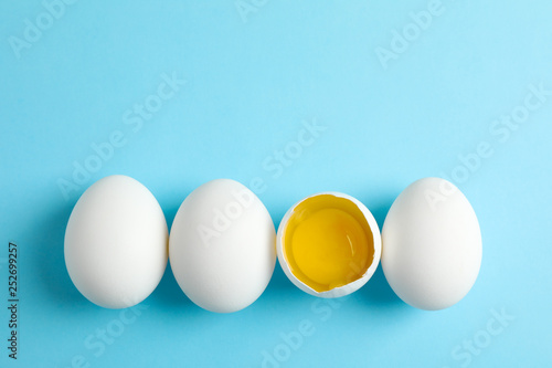 Chicken eggs and half with yolk on color  background, space for text
